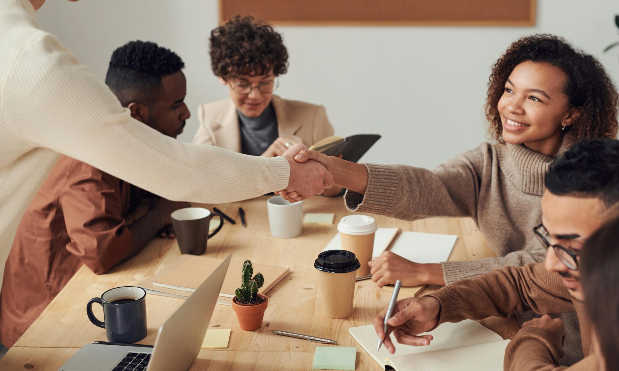 People sitting at a table. One woman shakes a person's hand.